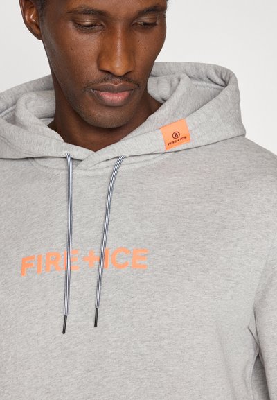 Mann trägt hellgrauen Hoodie mit orangefarbenem "FIRE + ICE"-Schriftzug und passendem orangefarbenem Markenschild auf der Kapuze, schaut nach unten.