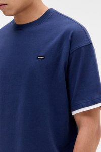 Marineblå kortærmet t-shirt lavet af bomuld, med rund halsudskæring og en kontrasterende hvid stribe på ærmerne. Indeholder et lille sort mærke.