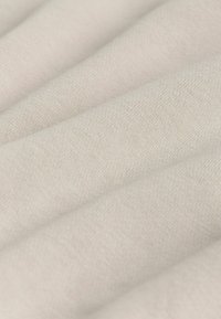 Šviesiai smėlio spalvos medvilnės audinys su tekstūruotu audiniu, turintis subtilius raukšles ir švelnų paviršių. Idealus įvairioms tekstilės aplikacijoms.