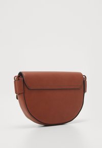 Borsa a tracolla in pelle marrone con forma arrotondata e chiusura a patta, dotata di tracolla regolabile e design elegante su uno sfondo bianco.