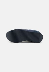 Semelle de sneaker bleu marine avec un dessous en caoutchouc texturé, des rainures profondes pour l'adhérence et une pointe arrondie lisse.