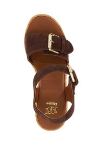 Sandale en daim marron avec deux larges sangles et une boucle dorée. Semelle intermédiaire en liège avec un coussin de pied lisse marron, comportant un détail de logo imprimé.