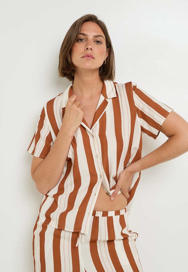 Set di pigiama in cotone a righe, composto da una camicia a maniche corte con bottoni in ruggine e crema, pantaloni corti con vita elastica abbinati e una texture liscia.