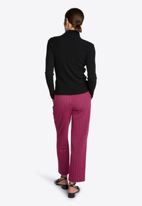 Černý žebrovaný rolák, kombinovaný s fialovými kalhotami se vzorem. Kalhoty mají geometrický potisk a rovný střih, doplněné sandály.