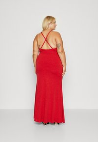 Red, sleeveless maxi dress with a fitted bodice and loose skirt. Features crisscross straps at the back and a subtle shimmer texture.