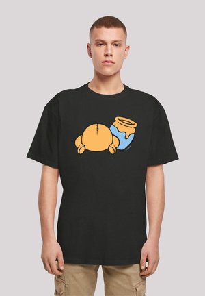 Black cotton t-shirt featuring a cartoon-style orange character next to a blue jar with a yellow lid. Short sleeves, loose fit.