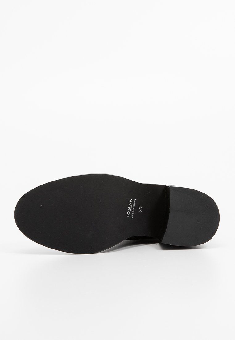 Suola di una scarpa elegante in pelle nera con tacco basso, marchio "UONA.K", taglia 37 e etichetta "Made in Portugal" visibile.