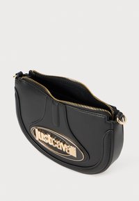 Borsa a tracolla in pelle nera con forma curva, hardware dorato, chiusura con zip e logo in vista. Tessuto liscio con un design elegante.