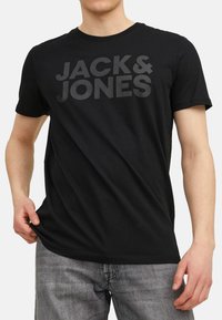 Schwarzes Baumwoll-T-Shirt mit fettem, dunkelgrauem Aufdruck "JACK & JONES" auf der Vorderseite. Kurze Ärmel und klassischer Rundhalsausschnitt.