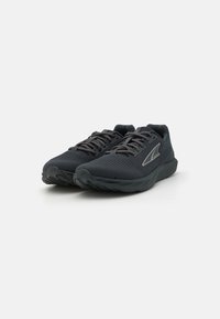 Chaussures de sport noires avec une tige en mesh respirant, lacets et semelle en caoutchouc. Présente un design épuré avec des accents gris subtils.