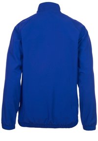 Blå vindjacka med hög krage, elastiska muddar och rynkad fåll. Tillverkad av lätt, slät material. Inga synliga logotyper eller mönster.