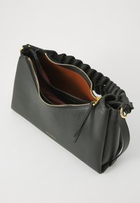 Black leather handbag featuring a textured surface, gold zipper, and a unique braided strap. Interior showcases a contrasting orange lining.
