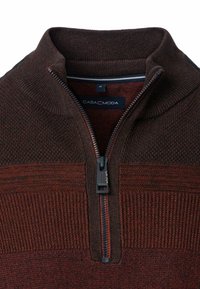 Strickpullover mit einem Reißverschlusskragen, der dunkelbraune und rostfarbene horizontale Streifen, strukturierte Muster und ein CASA MODA Etikett aufweist.