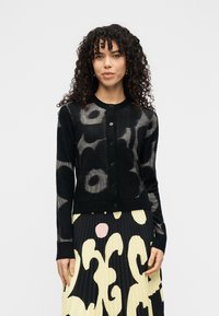 Μαύρη ζακέτα με ανθισμένο μοτίβο σε γκρι, διαθέτει στρογγυλή λαιμόκοψη, εμπρόσθιο κούμπωμα με κουμπιά και υφασμάτινη πλεκτή υφή.