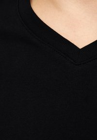Sort V-hals t-shirt med en glat tekstur, der har en forstærket halsudskæring og diskrete syninger.