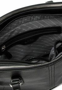 Black leather handbag interior features a textured black lining with gray stripes, zipped compartments, and a secure strap.