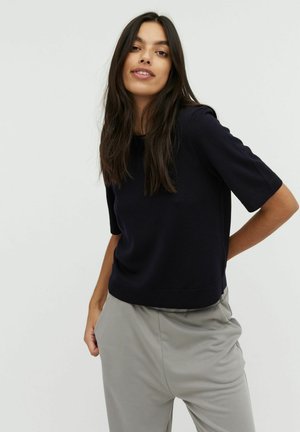 Maglietta a maniche corte in maglia blu navy con scollatura rotonda, caratterizzata da una vestibilità comoda e una texture morbida, abbinata a pantaloni grigi chiari.