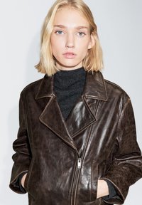 Braune Lederjacke mit Reverskragen, Reißverschluss und Seitentaschen. Weiche, strukturierte Oberfläche mit sichtbarem Glanz.