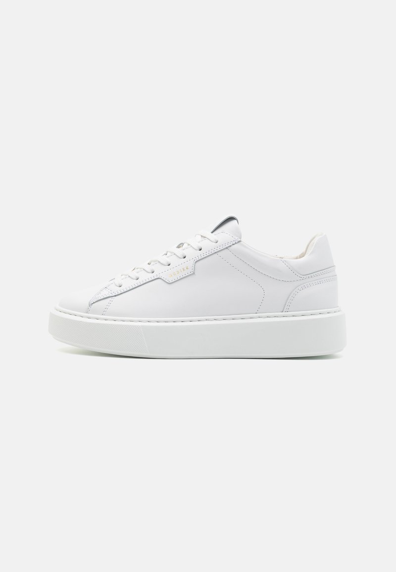 Hvite lær sneakers med flat gummisåle, snøring, minimal søm og subtilt merke på siden. Glatt tekstur.