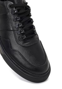 Baskets en cuir noir avec une tige texturée, bout rond et lacets noirs. Présente des œillets noirs et une semelle en caoutchouc avec une adhérence texturée.