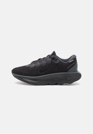 Czarny siateczkowy but do biegania Nike z grubą, amortyzowaną podeszwą, sznurowanym przodem i metką Gore-Tex w pobliżu wyściełanego kołnierza przy kostce.