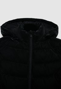 Giacca a vento nera con colletto alto, texture liscia, zip nascosta e cordini con chiusura regolabile sul cappuccio.