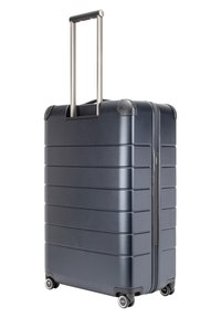 Valise rigide en bleu foncé avec une texture striée, poignée télescopique et quatre roues pour la mobilité, avec des accents de coin durables.