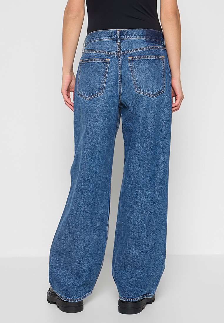 Hochtaillierte, weit geschnittene Jeans aus Denim in mittlerem Blau. Verfügt über fünf Taschen und dezente Nähte. Das Material hat eine strukturierte Oberfläche.