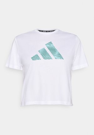 Hvit t-skjorte med korte ermer som har en cropped design og et tealfarget stripete Adidas-logo på framsiden. Myk, lett stoffkvalitet.
