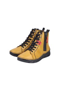 Bottes de cheville en cuir jaune avec des lacets noirs, un détail de fermeture éclair et des semelles en caoutchouc. Coutures remarquables et une étiquette d'accent rouge sur la fermeture éclair.
