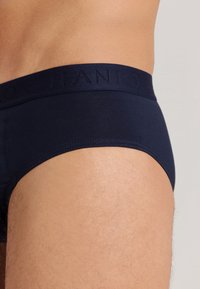 Slip blu navy realizzati in un tessuto liscio ed elasticizzato. La vita presenta un marchio in rilievo, con una vestibilità aderente e senza motivi visibili.