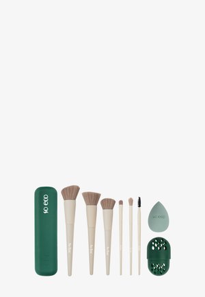 Set aus sechs beigen Makeup-Pinseln, einem grünen Makeup-Schwamm, einem grünen Schwammhalter und einer grünen Pinselbox, alle markiert mit "So Eco" auf weißem Hintergrund.