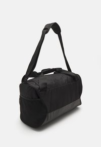 Borsa a duffle nera realizzata in materiale tessile e mesh, forma rettangolare, maniglia superiore imbottita e tracolla regolabile per un facile trasporto.