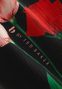 Bloemstof met een zwarte achtergrond met rode rozen en groene bladeren. Bevat de tekst "b by Ted Baker" in lichtroze.