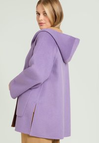 Paarse wolmix jas met een capuchon en zijslitsen, met een gladde textuur en een losse pasvorm. Contrasterende tan binnenvoering zichtbaar.