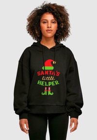 Čierna mikina s kapucňou, na ktorej je nápis "Santa's little Helper" v červenej, zelenej a zlatej farbe. Súčasťou je červený elfí klobúk a pruhy v zelenej a červenej farbe.