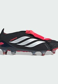 Μαύρο και κόκκινο ποδοσφαιρικό παπούτσι Adidas Predator με λευκές ρίγες, καλυμμένα κορδόνια και μεταλλικά πέλματα σε διάφανη σόλα.