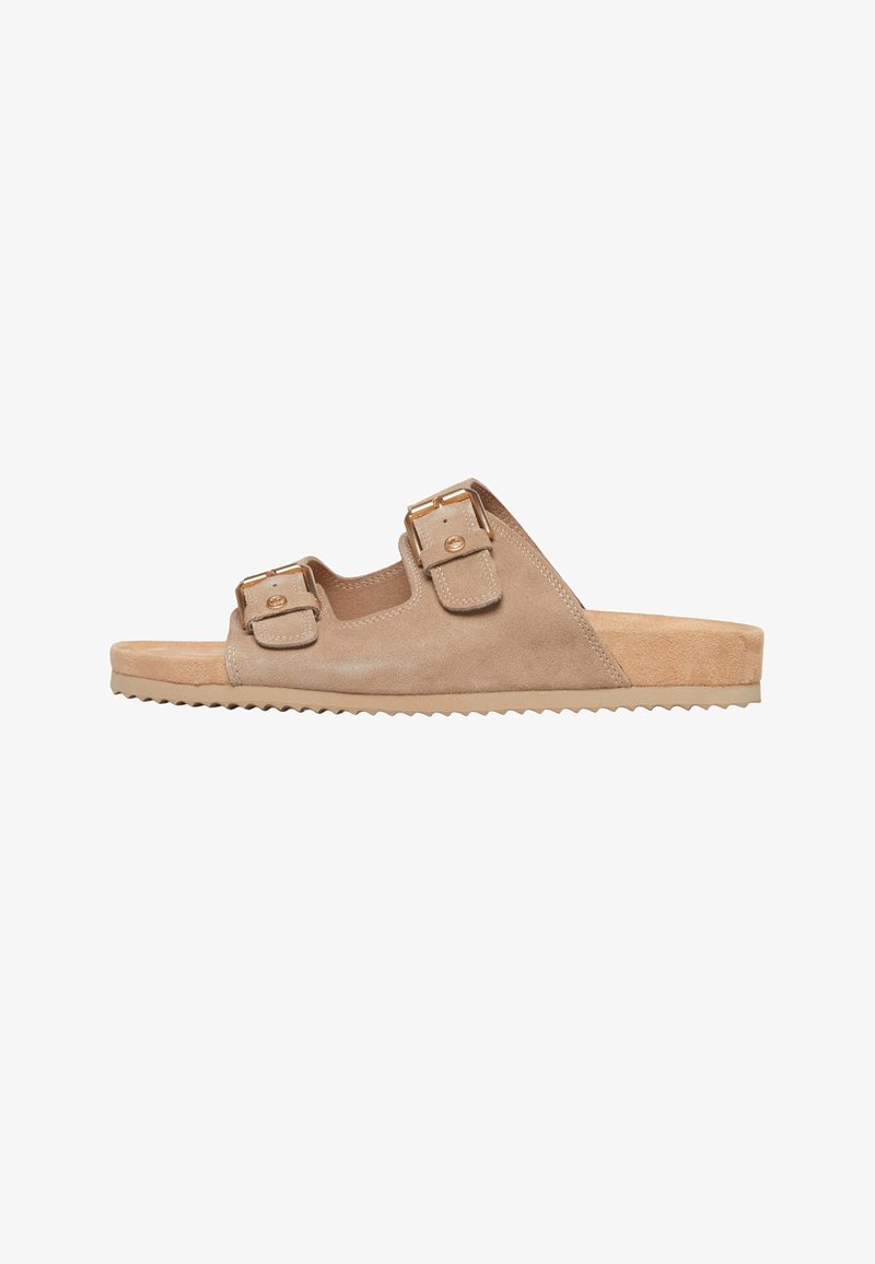 Mule en daim beige avec deux brides ajustables et boucles dorées, semelle plate avec grip texturé.
