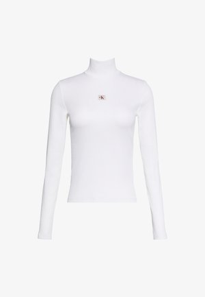 Haut blanc à manches longues avec col roulé et petit patch logo Calvin Klein centré sur la poitrine sur fond blanc uni.