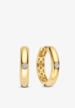 Een paar glanzende gouden oorringen, elk bezet met een enkele ronde diamant en met een honingraatpatroon aan de binnenrand, zichtbaar aan één oorbel.