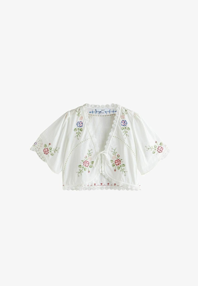 Blusa corta de manga corta blanca con ribete de encaje y bordado floral en rosa y azul, con cierre frontal de lazo.
