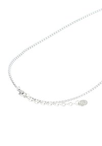 Srebrny naszyjnik łańcuszkowy z delikatnym, okrągłym wzorem ogniw, z zapięciem i małą markową zawieszką blisko zapięcia.