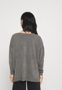 Grauer, übergroßer Strickpullover mit weitem Ausschnitt und langen Ärmeln. Weicher Stoff, gerippte Bündchen und lockere Passform mit geradem Saum.