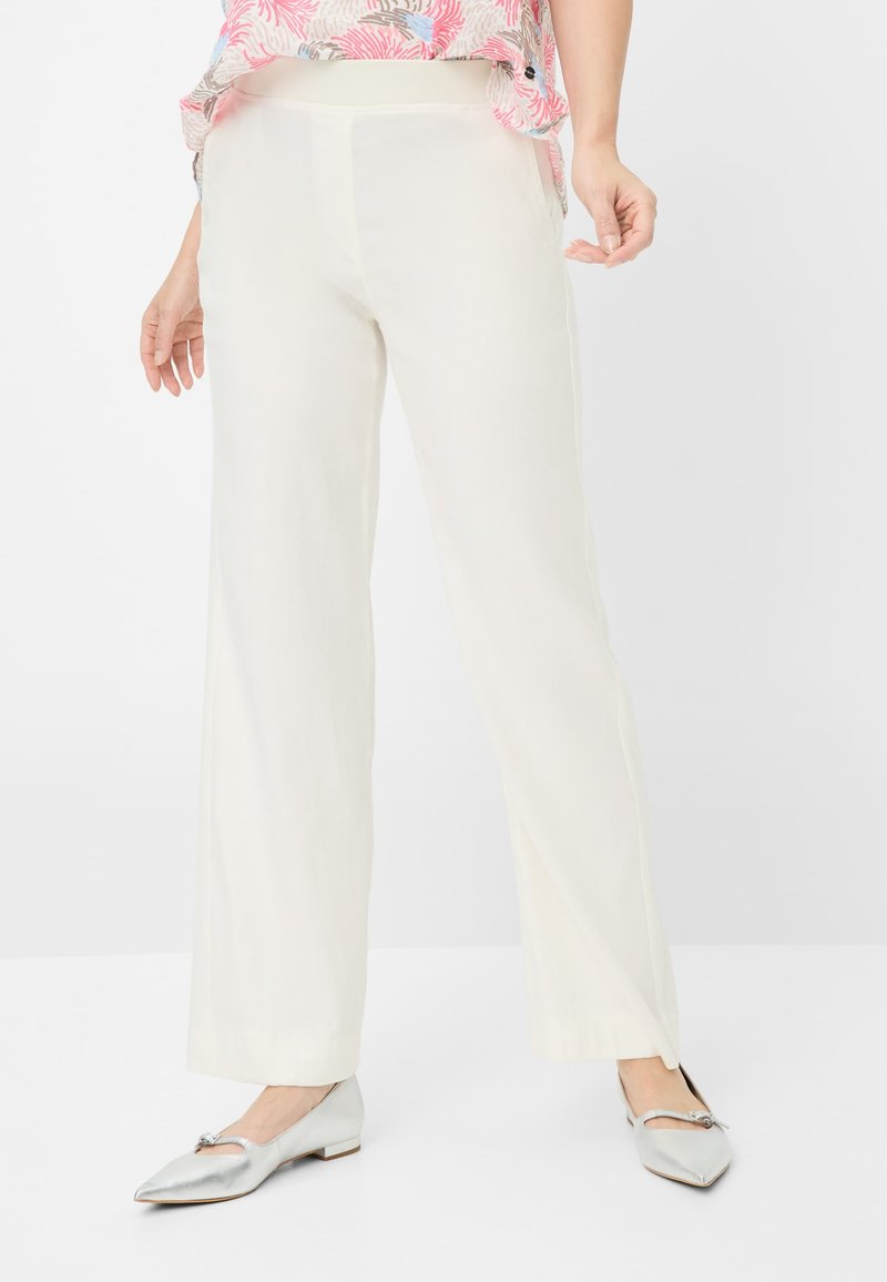 Witte, lichte, vloeiende broek met een rechte snit. Gecombineerd met glanzende zilveren flats met een decoratief accent aan de voorkant.