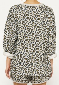 Set di abbigliamento da casa con stampa leopardata che include una maglia morbida e comoda con maniche a sbuffo e pantaloni corti coordinati, realizzato in un tessuto morbido e textured nei toni neutri.