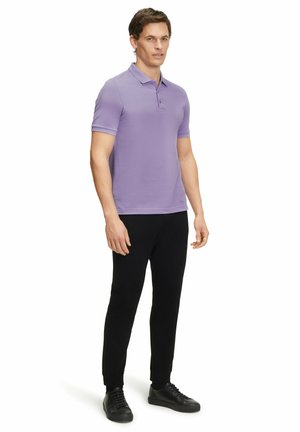 Lichtpaarse polo met korte mouwen, gecombineerd met zwarte tapered broek en zwarte sneakers. Glad materiaal met een klassieke pasvorm.