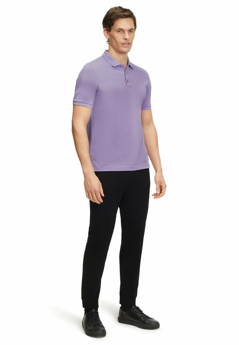 Polo shirt violet clair à manches courtes, associé à un pantalon noir fuselé et des baskets noires. Tissu lisse avec une coupe classique.