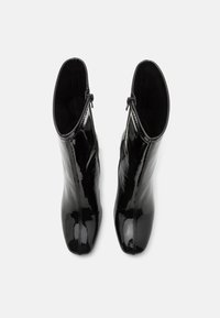 Cizme negre din piele patentată, cu un design elegant, având un fermoar pe lateral și vârf ascuțit. Textură netedă cu finisaj lucios.