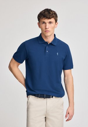 Navyblauwe polo met korte mouwen, kraag en een drieknops sluiting. Heeft een klein geborduurd logo op de borst.