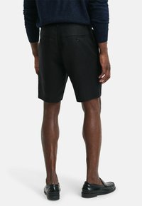 Schwarze Leinen-Shorts mit geradem Schnitt, ausgestattet mit zwei Gesäßtaschen mit Knopfverschlüssen und einer glatten, strukturierten Oberfläche.